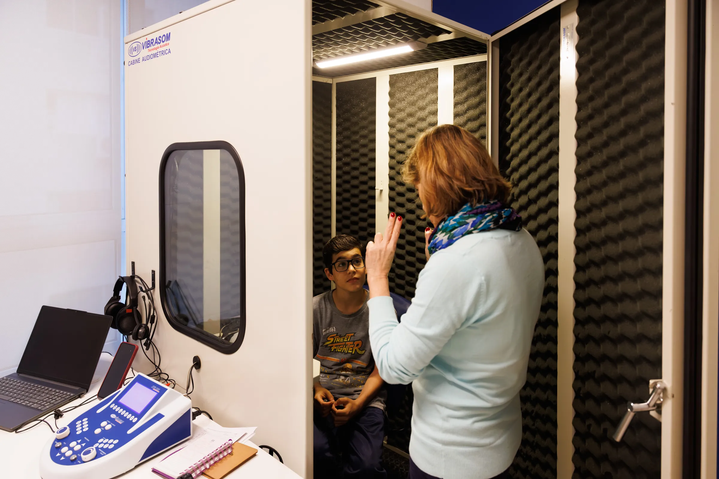 Simone conversando com o paciente na porta da cabine audiométrica